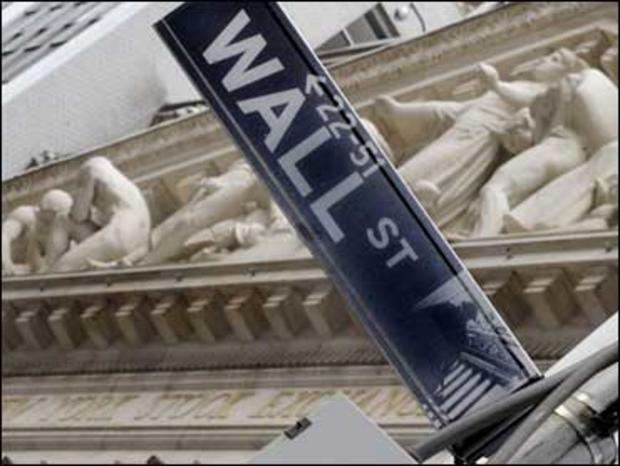 The Wall Street sign is juxtaposed against the sculpture on the facade of the New York Stock Exchange 