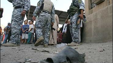 A shoe of one of the victims, is seen, on the ground as Iraqi forces stand guard the area after a car bomb explosion in the predominantly Shiite Bayaa district, southwestern Baghdad, Iraq, on Oct. 12, 2008. 