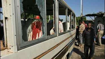 Iraqi civilians inspect a damaged bus after bombs exploded in Baghdad 