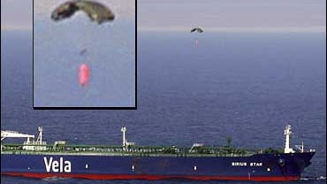 A parachute dropped by a small aircraft drops over the MV Sirius Star at anchor 