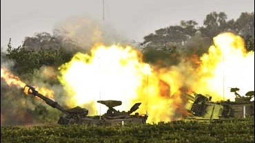 An Israeli army mobile artillery piece fires towards targets in the Gaza Strip 