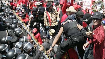 Riot policemen block protesters from trying to cross the fense in front of the prime minister's office in Bangkok 