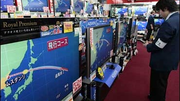 A salesclerk checks flat panel TVs showing the route of a rocket launched by the North Korea from its Musudan-ri facility in the northeastern part of the country over Japan at Onoden electric appliances shop in Tokyo 