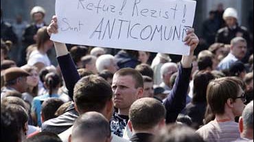 A protestor hold up a sign in front of the government building which reads "Refuse, Resist, We Are Anti-Communists" in Chisinau, Moldova 