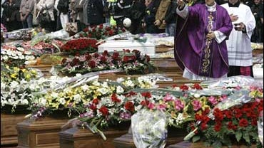 Cardinal Tarcisio Bertone, right, sprinkles holy waters on coffins during the funeral service for quake victims in L'Aquila, central Italy 