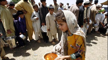 A child carries a bowl of hot food past others lining up to get theirs in a refugee camp near Mardan, in northwest Pakistan, Saturday, May 9, 2009. 