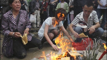 Chinese parents burn papers and candles during the one year anniversary of the earthquake that caused the Beichuan middle school to collapse killing around 1,000 students and teachers in Beichuan, southwestern China's Sichuan province, Tuesday, May 12, 20 