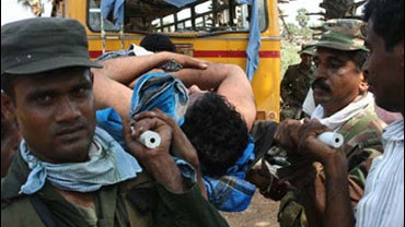Sri Lankan army soldiers attend a wounded ethnic Tamil civilian in Kariyalamullivaikal, Sri Lanka, Saturday, May 16, 2009. 