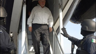 In this photo released by Mexico's Federal Public Safety Department (SSPF), an unidentified detainee exits a police airplane as federal police stand guard in an undisclosed location, Tuesday May 26, 2009. 