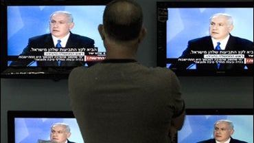 An Israeli man looks at Israeli Prime Minister Benjamin Netanyahu during a speech on television screens at a shop in Jerusalem, Sunday June 14, 2009. Netanyahu has called for creation of a limited Palestinian state for the first time, saying it must be di 