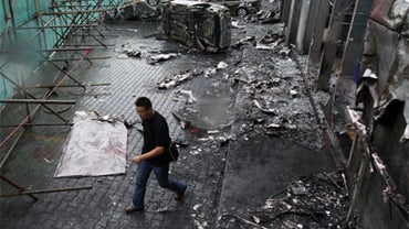 A man walks across a destroyed car dealer in the Uighur section in Urumqi, western China's Xinjiang province, Wednesday, July 15, 2009. The capital was calm Wednesday, although security was tight, especially near Uighur areas after Monday's fatal shooting 