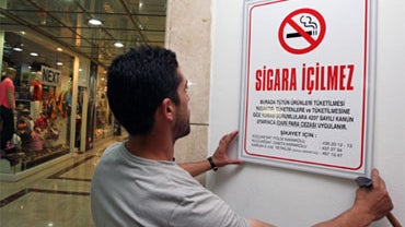 A man hangs a no-smoking sign at the Karum shopping mall in Ankara, Turkey, Thursday, July 16, 2009. 