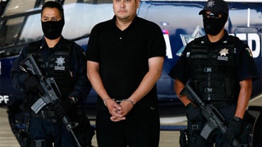 Police officers escort Jose Alberto Lopez, an alleged coordinator for the Mexican drug cartel known as "La Familia," during his presentation to the media in Mexico City, July 22, 2009. 