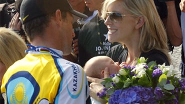 Third-placed overall, American seven-time Tour de France winner Lance Armstrong, left, is greeted by his girlfriend Anna Hansen, right, holding their son Max 