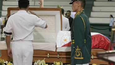 A military officer salutes the flag-draped casket of former Philippine President Corazon "Cory" Aquino during a wake at a Catholic university gymnasium at suburban San Juan, east of Manila, Philippines Saturday Aug. 1, 2009. 