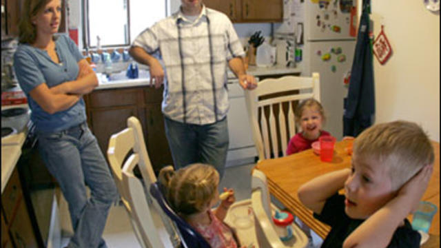 In this photo made Saturday, July 11, 2009, Mary and Chad Pugh supervise snack time at their kitchen table with their children Jack, 3, right, and Marian, 1, center, and their friend Eva Evans, 3, at their home in Watertown, Mass. As parents face reduced  