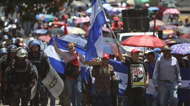 Supporters of Honduras' ousted President Manuel Zelaya demonstrate as riot police walk along side them in Tegucigalpa, Friday, Sept. 11, 2009. Zelaya was ousted by a coup in June. 
