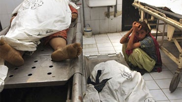 A Pakistani girl mourns beside her mother's body, center, who was died in the stampede, at the mortuary of a local hospital in Karachi, Pakistan on Monday Sept. 14, 2009. At least 18 women and girls waiting to get free flour in Pakistan's southern city of 