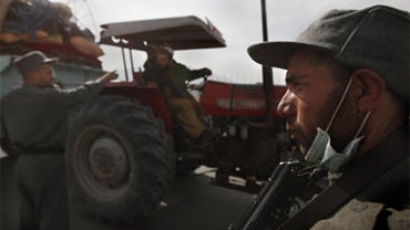 An Afghan police officer orders a driver to stop as another stands guard at a roadside checkpoint in Kabul, Afghanistan, Saturday, Nov. 7, 2009. 