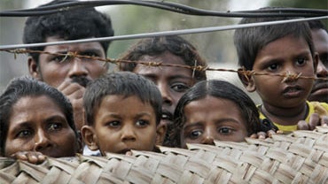 Internally displaced Sri Lankan Tamil civilians peep from over a fence at a camp for the displaced in Vavuniya, Sri Lanka, Saturday, Nov. 21, 2009. 