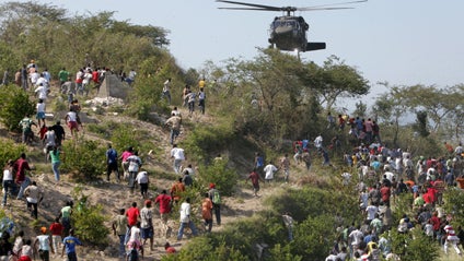 People run toward a U.S. helicopter as it makes a water drop near a country club used as a forward operating base for the U.S. 82nd Airborne Division in Port-au-Prince, Haiti, Saturday, Jan. 16, 2010. 