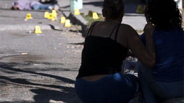 Relatives look at the dead body of Ali Rene Paez, 24, which lies on the crime scene where he and another man were killed and other three people injured by unknown gunmen in Ciudad Juarez, northern Mexico, Thursday, April 8, 2010. 