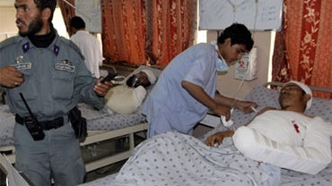 A medic helps a man wounded in a blast in Kandahar city, south of Kabul, Monday, April 26, 2010.  