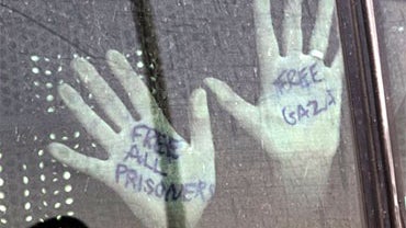 The hands of a detained activist from the Gaza-bound flotilla are placed on a bus window as it leaves a prison in Beersheba, southern Israel, on the way to Israel's airport, Wednesday, June 2, 2010. Israel on Wednesday quickened its expulsion of detained  