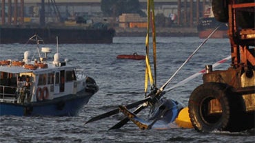 A crane lifts a crashed helicopter in Hong Kong Victoria Harbor Saturday, July 3, 2010. 