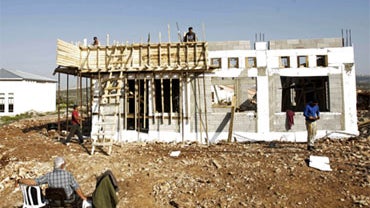 A Jewish settler (in foreground) looks on as Palestinian construction workers build a synagogue at the Jewish settlement of Kedumim, in the northern West Bank in this December 2009 file photo. Jewish settlers have refused to abide by a government-ordered  
