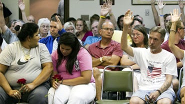 Two women in the front react to a show of hands of Fremont citizens who agree with a speaker who was in favor of implementing a city ordinance against illegal immigrants, in Fremont, Neb., Tuesday, July 27, 2010. A voter-approved ban on hiring and renting 