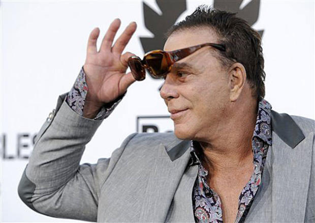 Mickey Rourke, a cast member in "The Expendables," takes off his sunglasses for photographers at the premiere of the film in Los Angeles, Tuesday, Aug. 3, 2010. (AP Photo/Chris Pizzello 