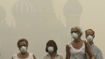 Tourists wear protective face masks as they walk along the Red square in thick smog, with Saint Basil's Cathedral partially visible in the back, in Moscow, Russia, Friday, Aug. 6, 2010. 