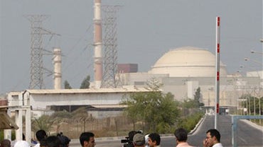 Media members stand at a gate of Bushehr nuclear power plant, Iran's first, with its reactor building in background, just outside city of Bushehr, 750 miles south of the capital Tehran, Iran, Friday, Aug. 20, 2010. Iranian and Russian engineers began load 