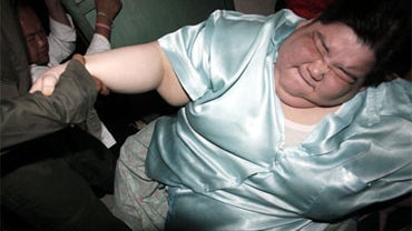 A volunteer helps 603-pound Umnuayporn Tongprapai stand as she is removed from her third-floor apartment and taken to a hospital in Bangkok, Aug. 26, 2010. 