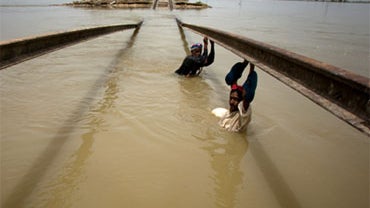 People use a damaged railway track to cross heavy floodwater in Sultan Kot, in southern Pakistan on Saturday, Aug. 28, 2010. 