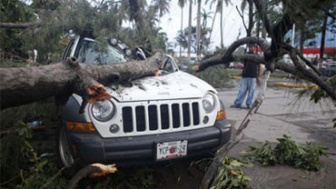 A man stands next to a vehicle damaged by a fallen tree due to the passage of Hurricane Karl in Veracruz, Mexico, Friday, Sept. 17, 2010.  