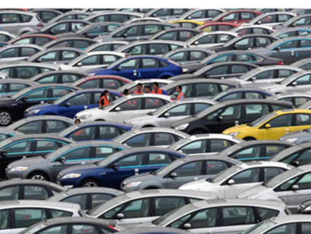 In this Aug. 25, 2010 photo, people stand near Ford cars at a plant of Changan Ford Mazda Automobile Co. in southwest China's Chongqing city. 