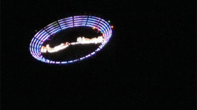 U.S. plastic artist Peter Coffin's "Flying Saucer" -- a 7-meter, LED-studded, SMS-controlled flying saucer lifted by a helicopter -- flies over Ipanema Beach May 23, 2009, in Rio de Janeiro, Brazil. AFP PHOTO/Antonio Scorza (Photo credit should read ANTON 