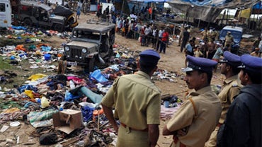 Police officials look on at the scene following a stampede at Pullumedu, some 210 km northeast of the southern Indian city of Kochi, on January 15, 2010. 
