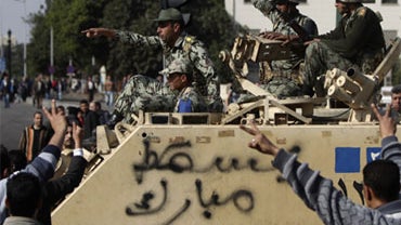 People gesture towards Egyptian soldiers aboard an armored personnel carrier, emblazoned with the words "Down Mubarak", in Cairo, Sunday, Jan. 30, 2011.  