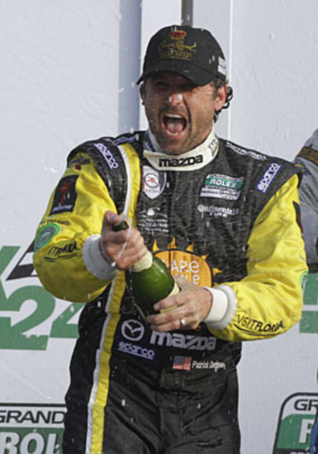 Driver and actor Patrick Dempsey sprays champagne on fellow drivers after he and his fellow drivers finished in third place in the GT class in the Grand Am Rolex 24 hour auto race at Daytona International Speedway in Daytona Beach, Fla., Sunday, Jan. 30,  