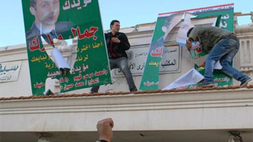 Egyptian demonstrators tear down posters of Egyptian President Hosni Mubarak's son Gamal Mubarak, in Alexandria, January 25, 2011. 