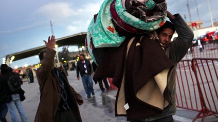 Egyptians, who have just crossed Salloum land port gate with Libya, at background, arrange their luggage on a mini bus, Feb.23, 2011. 