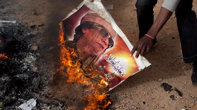 Protesters burn a Muammar Qaddafi poster 