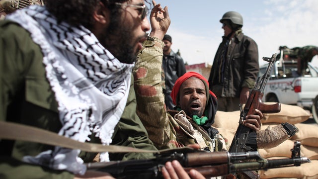 A former Libyan army soldier, foreground, shows new Libyan rebel recruits how to use an assault rifle during a training session after they signed up with forces opposed to Libyan leader Moammar Gadhafi, at a training base in Benghazi, eastern Libya, March 