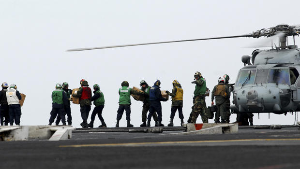 sailors move food and water onto an HH-60H Sea Hawk 