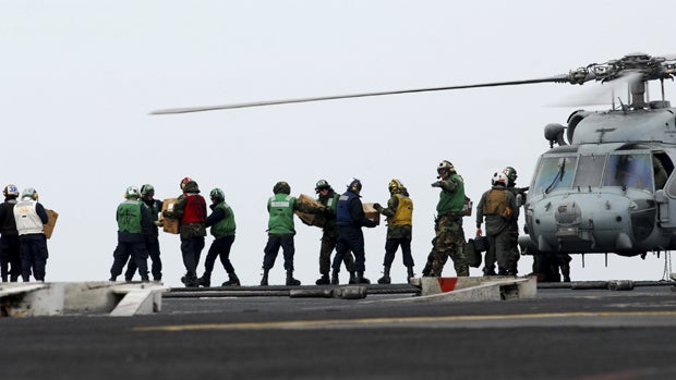 sailors move food and water onto an HH-60H Sea Hawk  