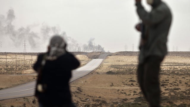 Rebels look at smoke rising from apparent NATO friendly fire air strike 