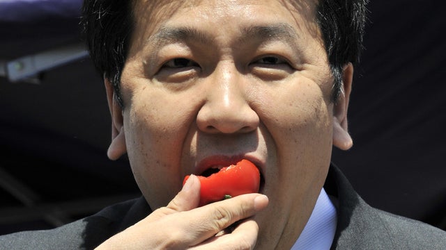 Japan's Chief Cabinet Secretary Yukio Edano eats a tomato 